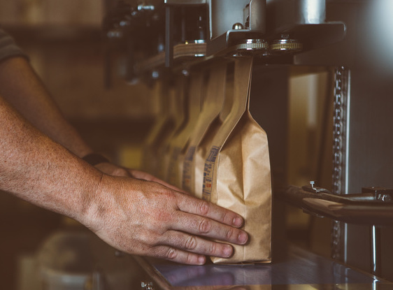 Unrecognizable man putting coffee bags in line / click_and_photo - stock.adobe.co Unrecognizable male arms putting wrapped coffee beans in row